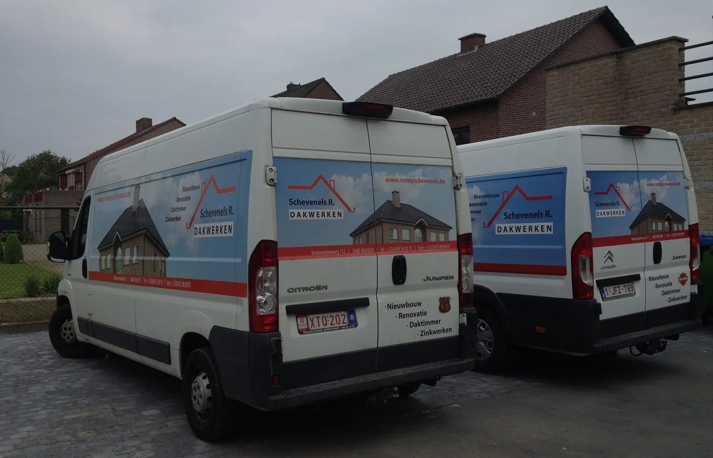 De twee belettererde bestelwagens van Schevenels R. Dakwerken naast elkaar