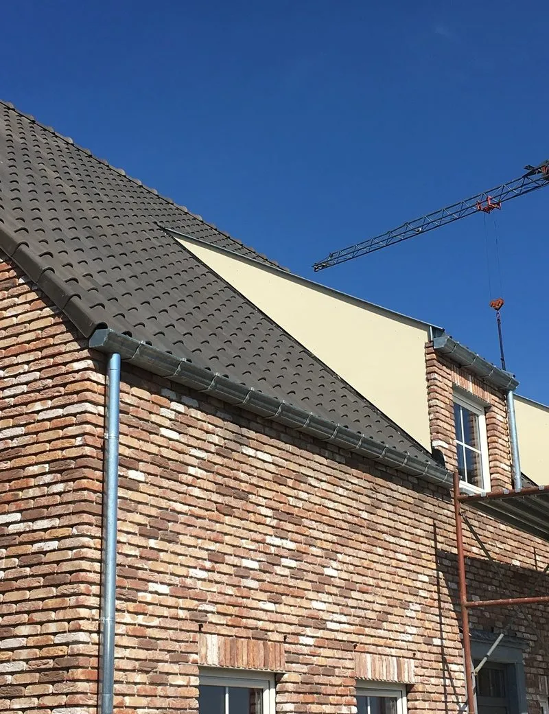 Afgewerkt nieuwbouwdak met pannen en zinken dakgoten, uitgevoerd door Dakwerken Ronny Schevenels