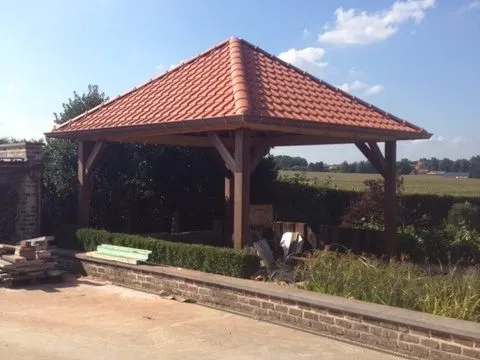 Afgewerkt poolhouse met piramidedak in rode pannen op houten staanders
