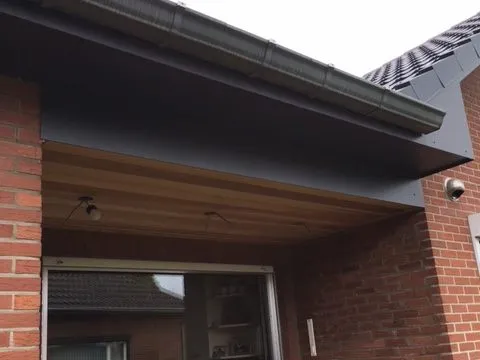 Afgewerkte dakrand met goot en een plafond in cederhout boven een terras